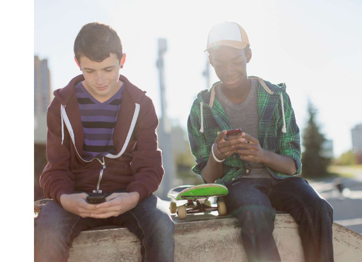 Une image sur une page Web concernant le site Web sur la santé mentale de Jeunesse, J'écoute de deux jeunes personnes assises à l’extérieur et envoyant des textos